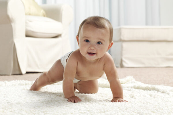 Baby in Pampers® Windel krabbelt über den Teppich