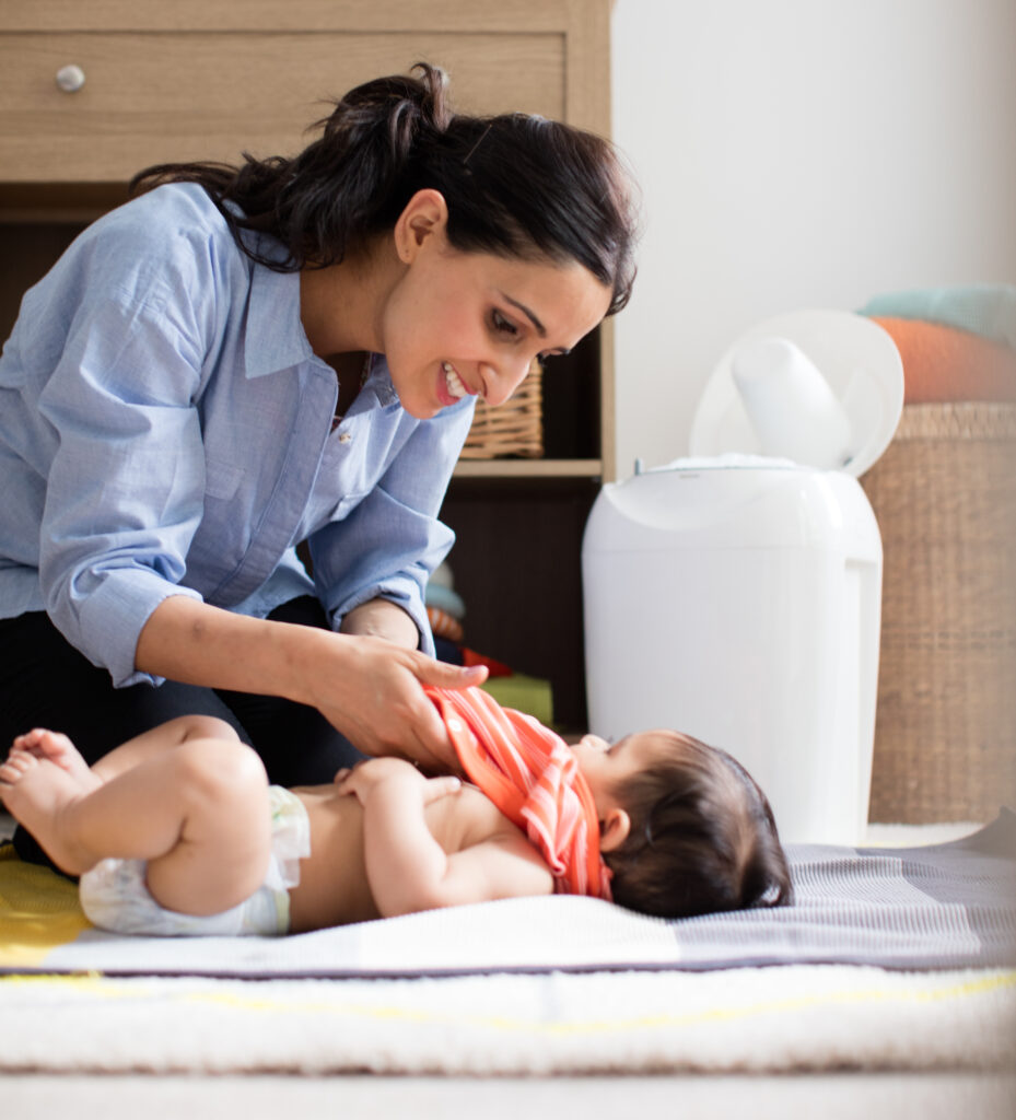 Mutter wickelt auf dem Boden ihr Baby und nutzt den Tommee Tippee Sangenic Tec-Windeltwister